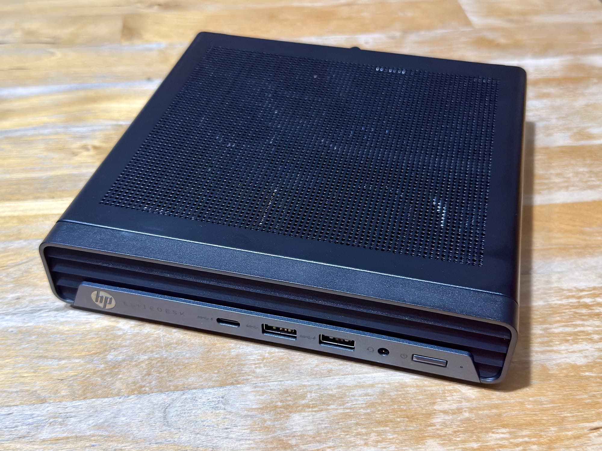 An HP EliteDesk mini PC on a wooden table.