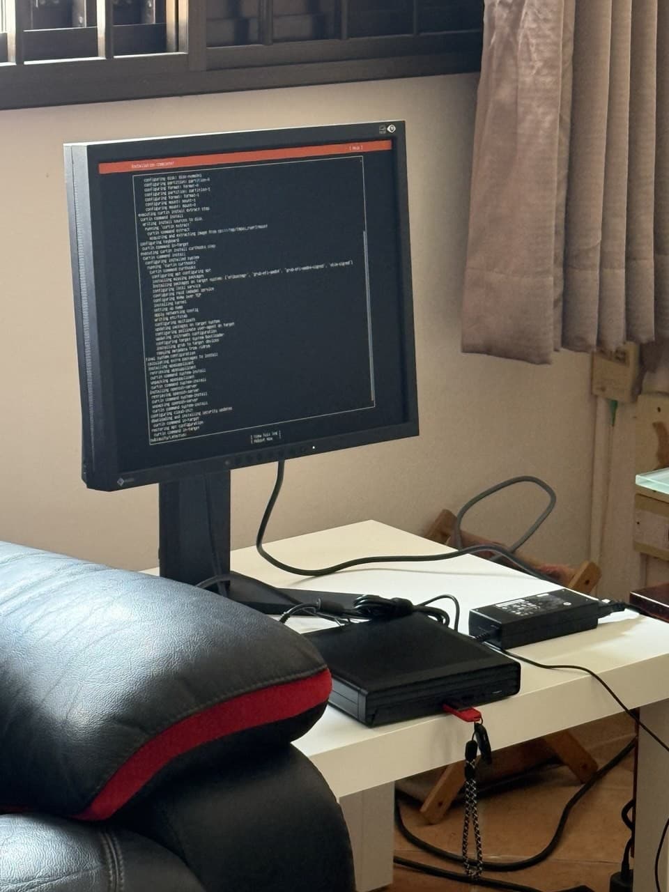 A monitor showing the Ubuntu Server installer log, connected to the mini PC on a small table.